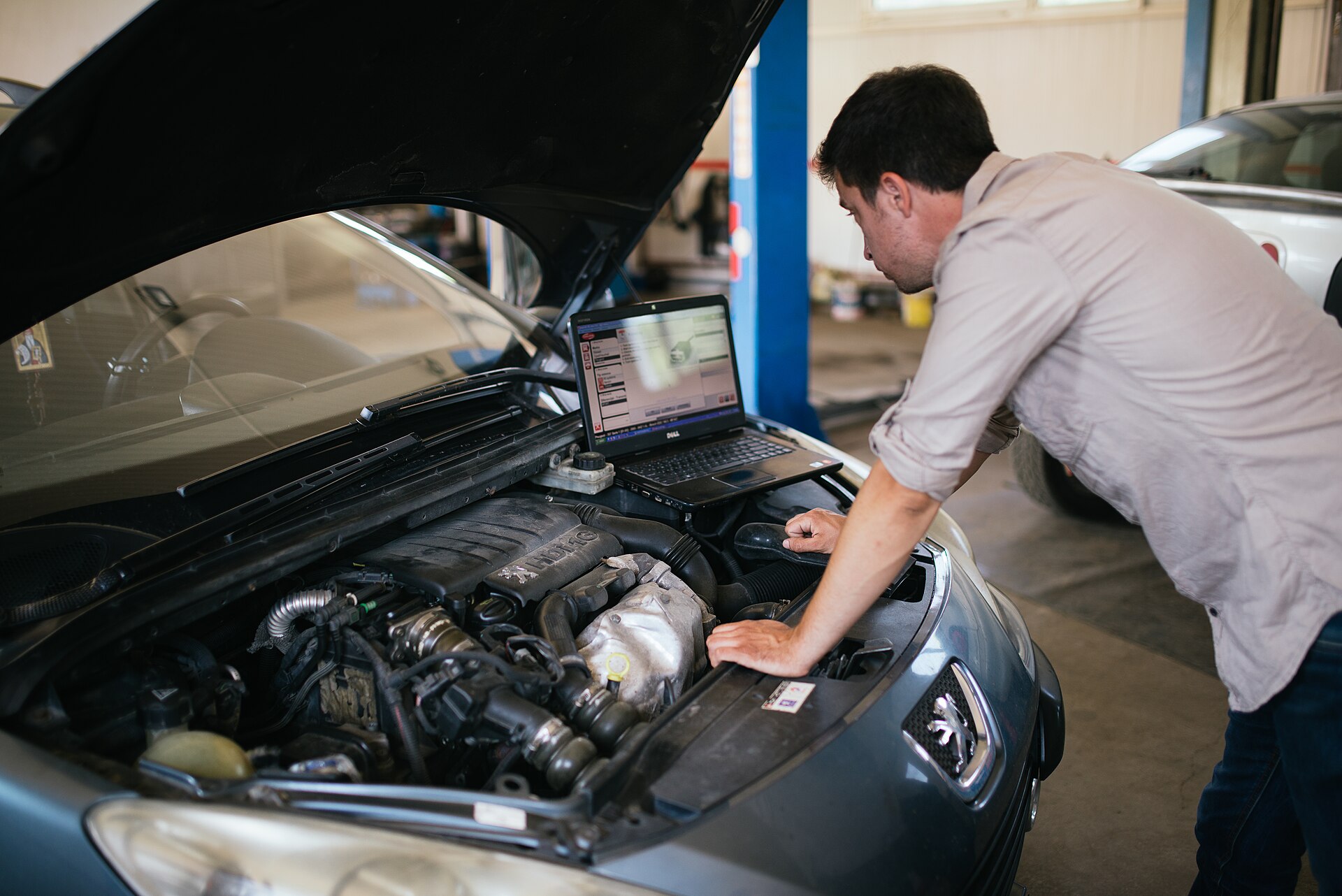A technician's gloved hands working under the hood with a diagnostic tool