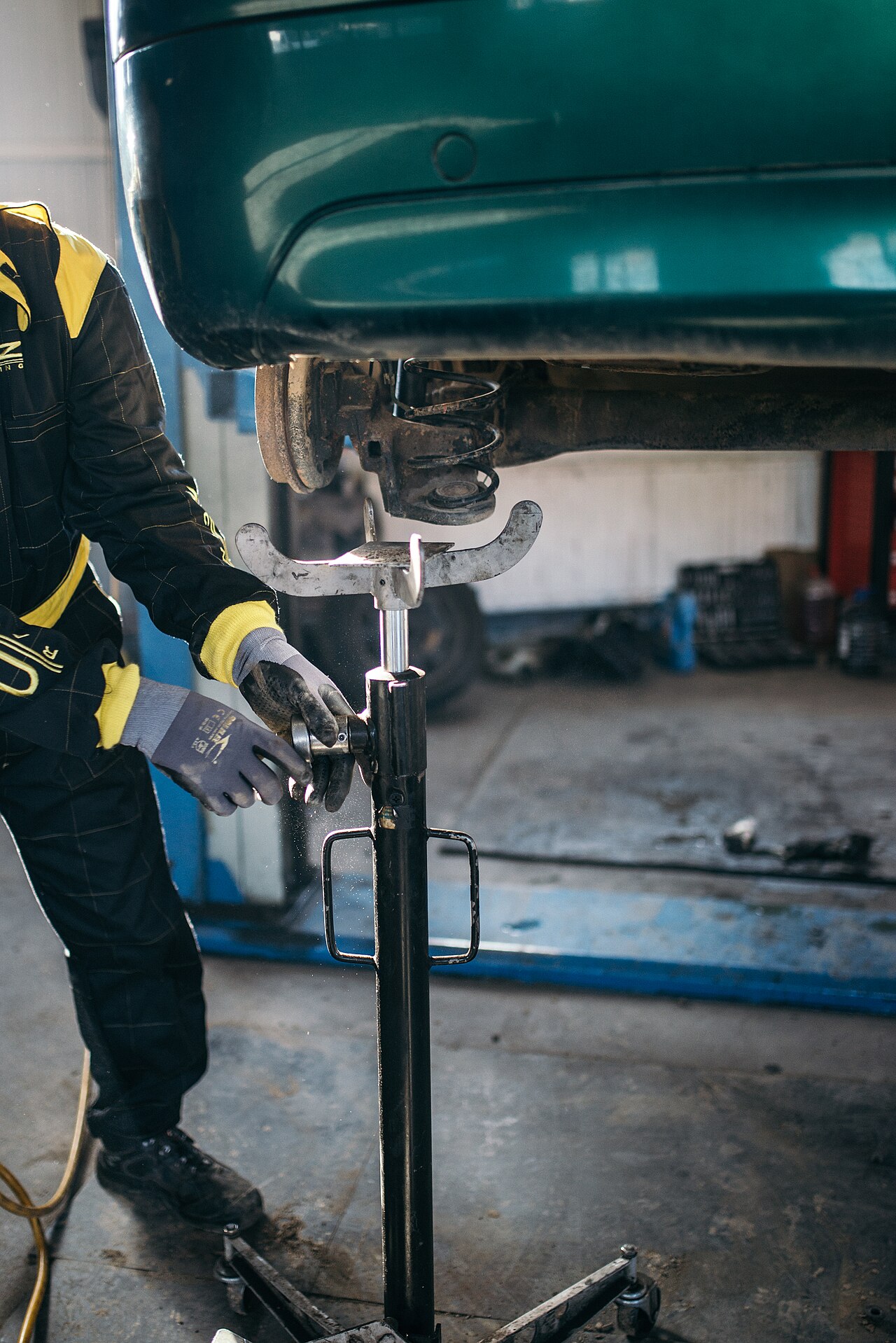 A technician working under a lifted vehicle in a repair bay
