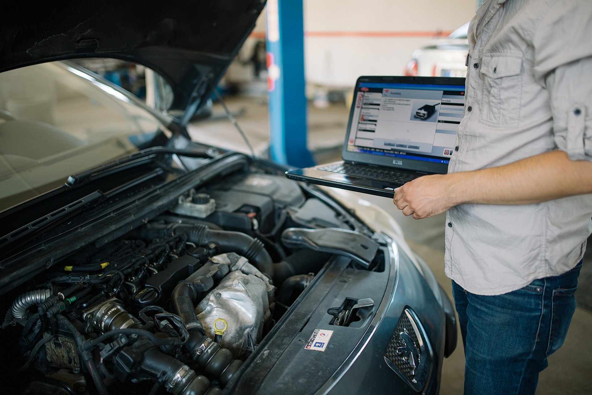 A technician working on suspension under a lifted vehicle